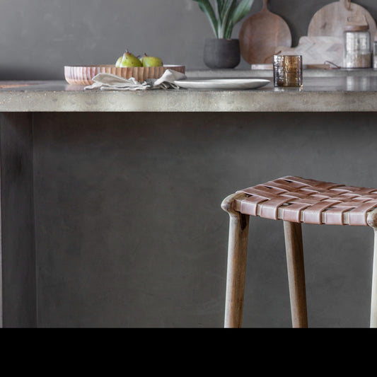 Nkuku Adembi woven leather counter stool in natural and brown with wooden legs, featuring a stylish and comfortable seating design.
