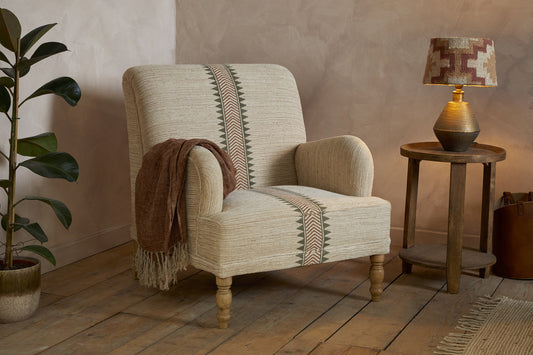 Nkuku Zairya jute and cotton armchair in natural and rust colors, showcasing its cozy, stylish design and soft fabric texture.