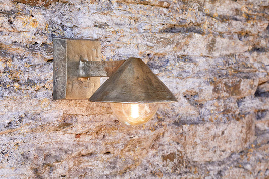 Rhya outdoor wall lamp in antique brass by Nkuku, showcasing a vintage-style outdoor lighting fixture mounted on a wall.